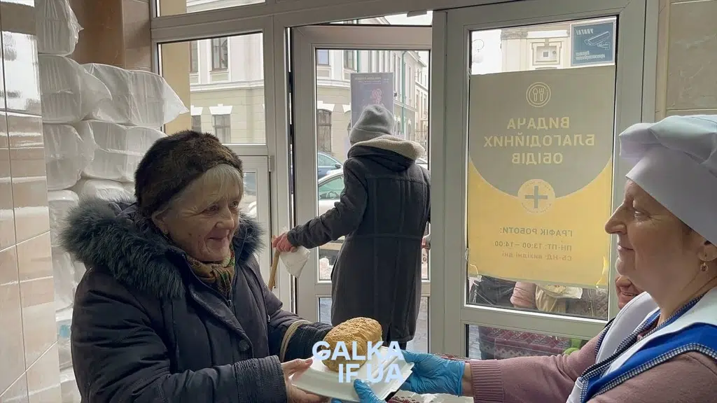 Волонтерка передає їжу літній жінці