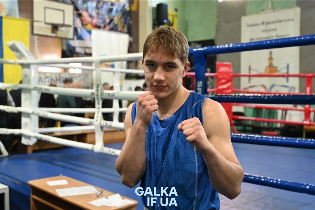 Боксер у синій формі позує біля рингу