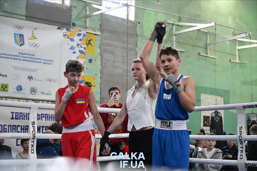 Юний боксер у синьому однострої святкує перемогу