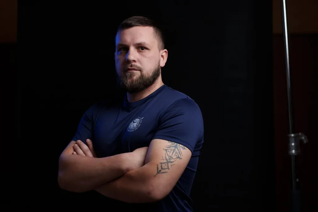 Чоловік у темно-синій футболці з татуюванням