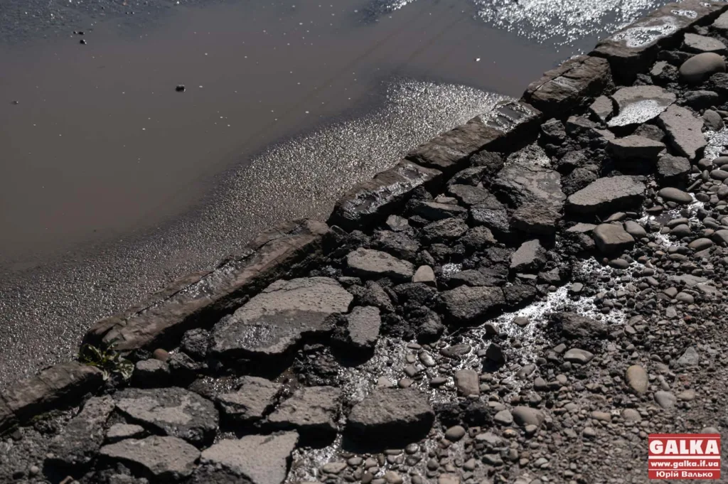 Пошкоджена асфальтна дорога біля калюжі