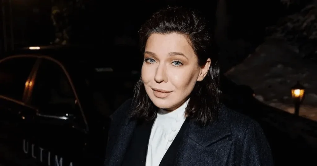 Жінка в темному пальті на вечірньому фоні