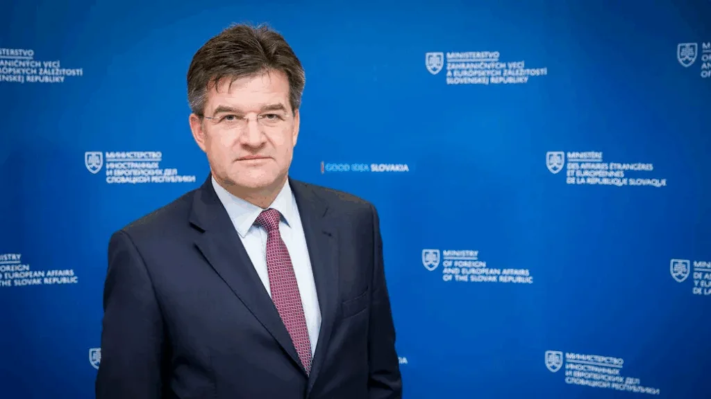 Чоловік у костюмі на тлі логотипу міністерства