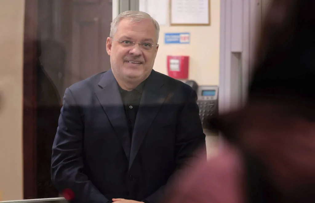 Чоловік у темному костюмі стоїть за склом