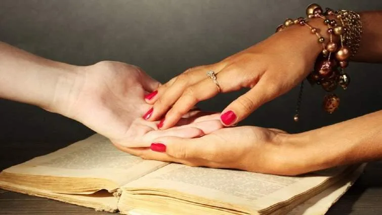 Ворожка читає долю по руці над книгою