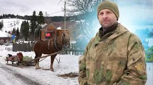 Чоловік у камуфляжі біля коня взимку