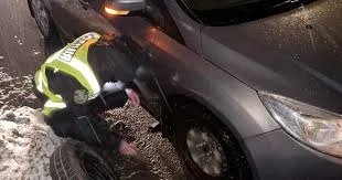 Поліцейський змінює колесо автомобіля взимку