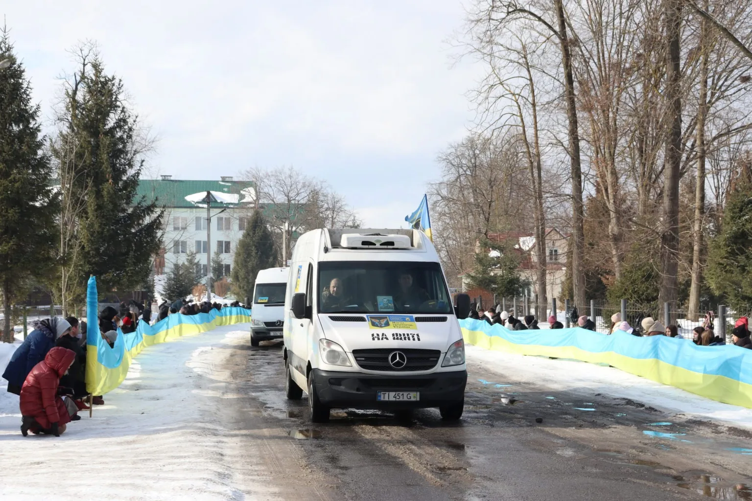 Мікроавтобуси з українськими прапорами на зимовій дорозі
