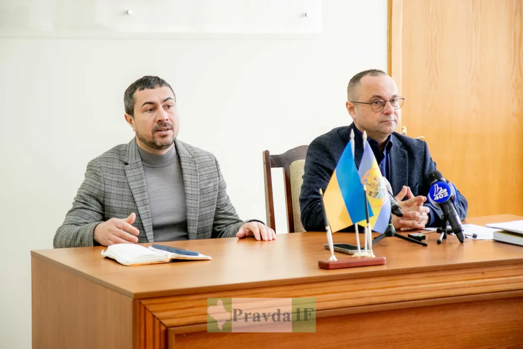 Двоє чоловіків на пресконференції з українськими прапорами