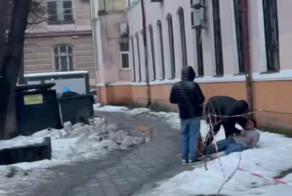 Двоє людей допомагають чоловіку, який лежить на снігу