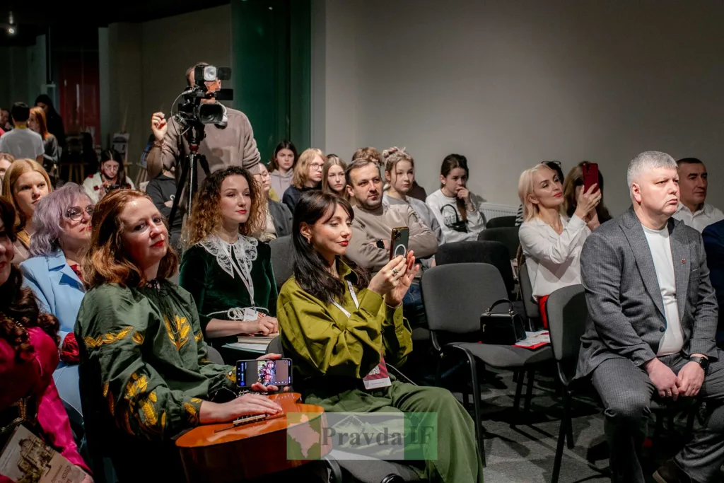 Люди на конференції слухають виступ і фотографують