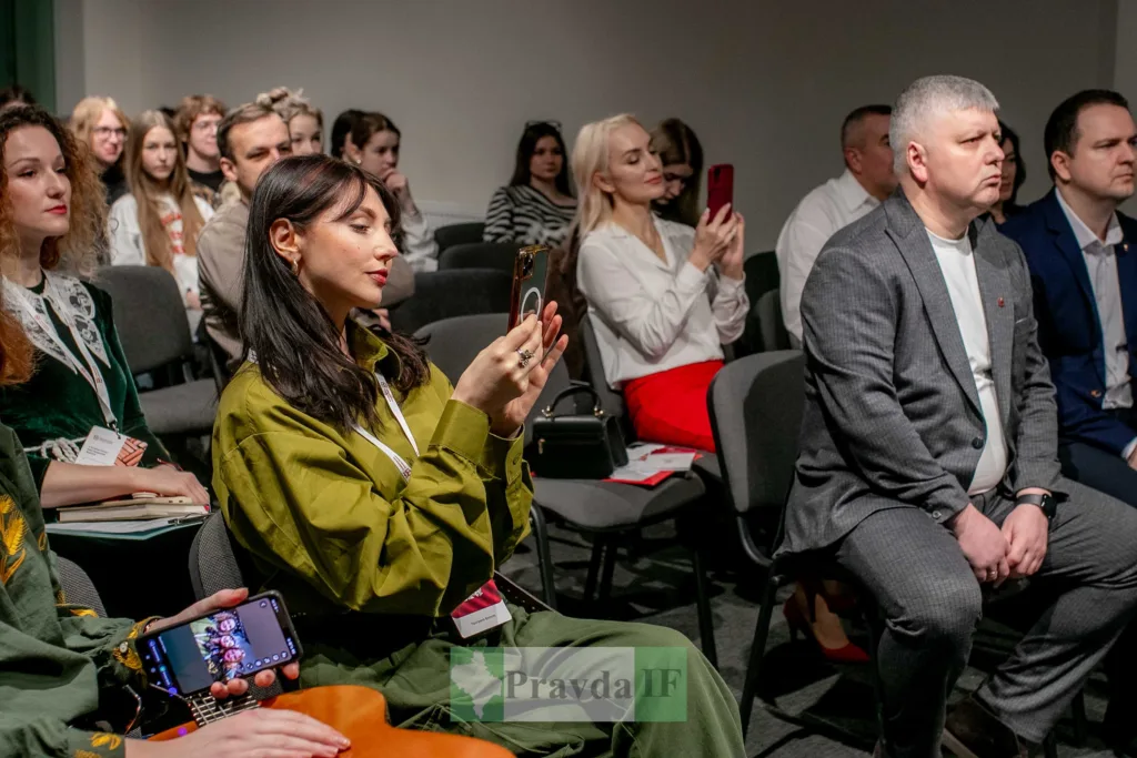 Учасники конференції слухають доповідь і фотографують