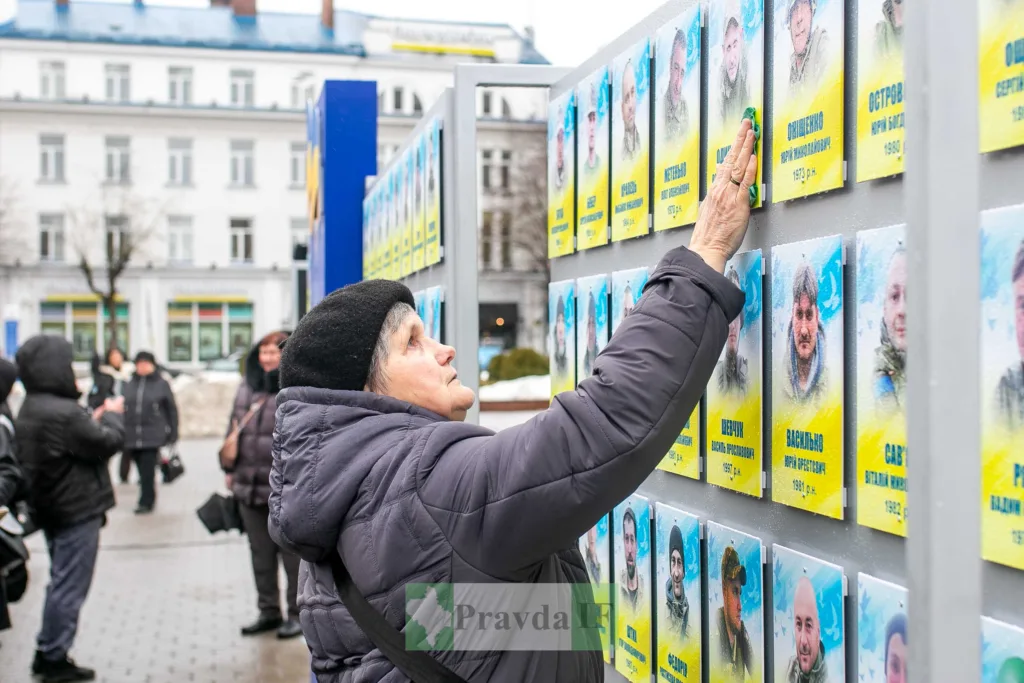 Жінка торкається меморіалу загиблих героїв України
