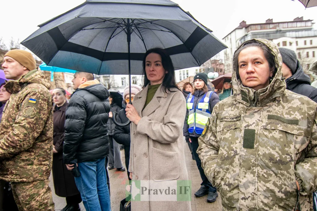 Люди на мітингу під парасолями в дощову погоду