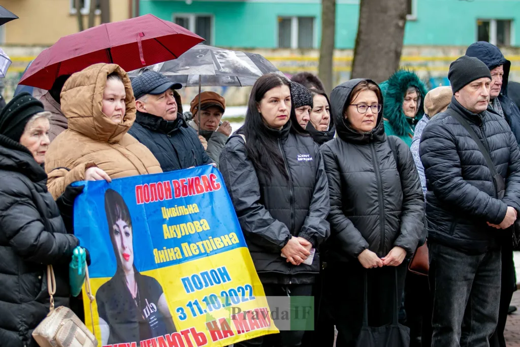 Люди на мітингу з плакатом під дощем