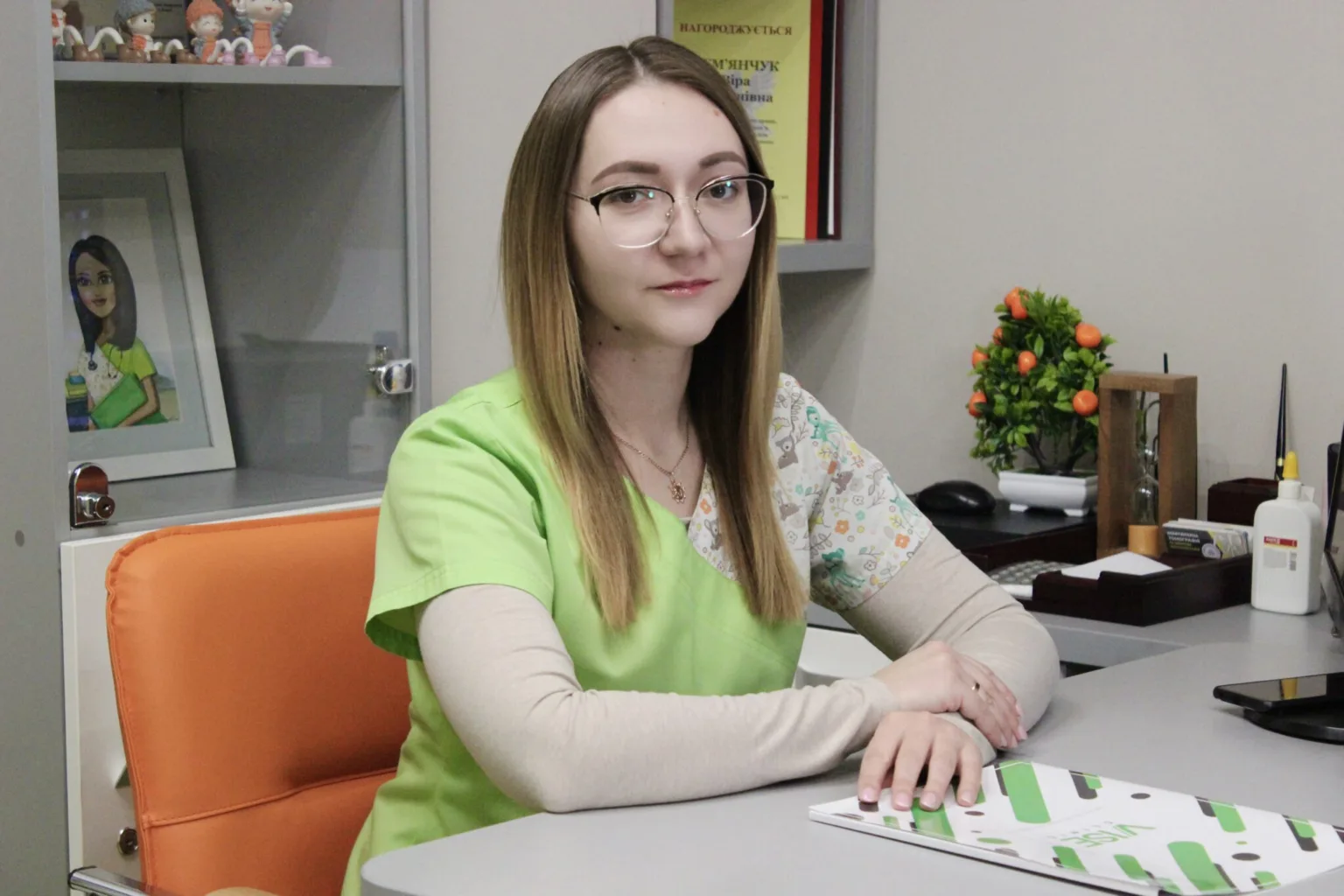 Жінка в медичному одязі сидить за столом