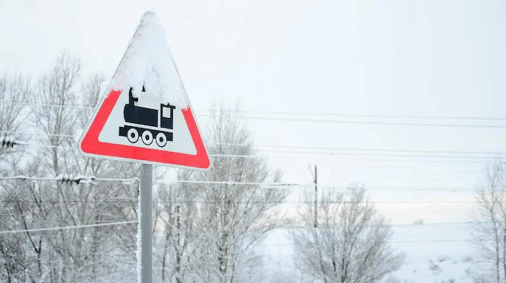 Засніжений знак попередження про залізничний переїзд