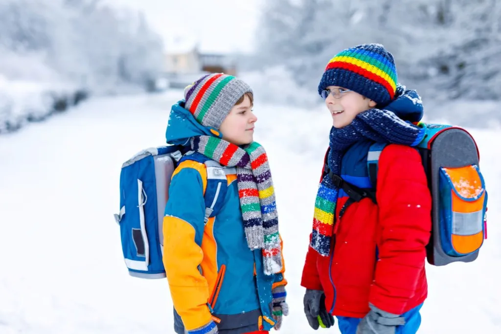 Двоє дітей із рюкзаками взимку на снігу