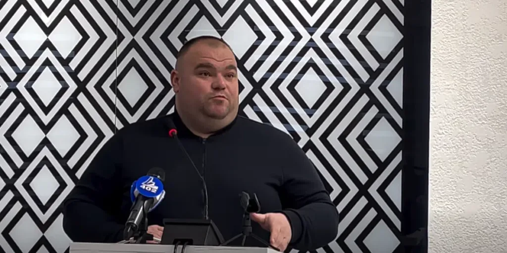 Чоловік виступає на пресконференції перед мікрофоном