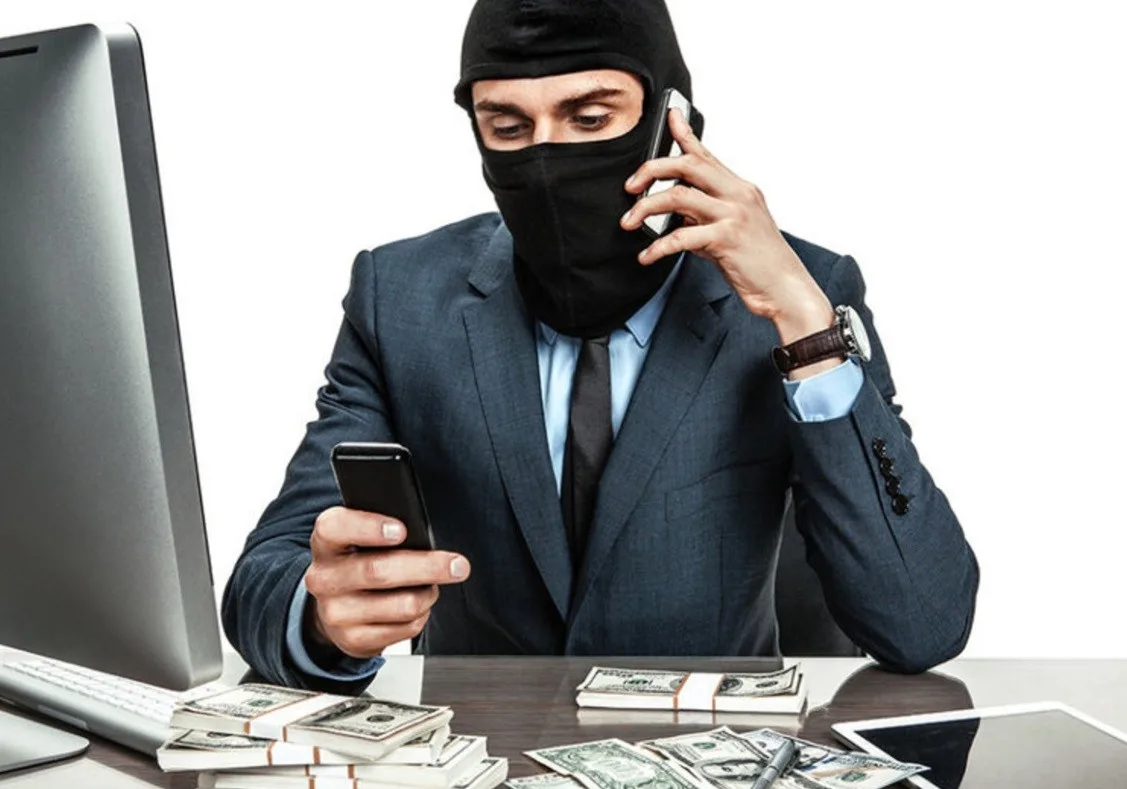 Шахрай у масці за комп’ютером з готівкою