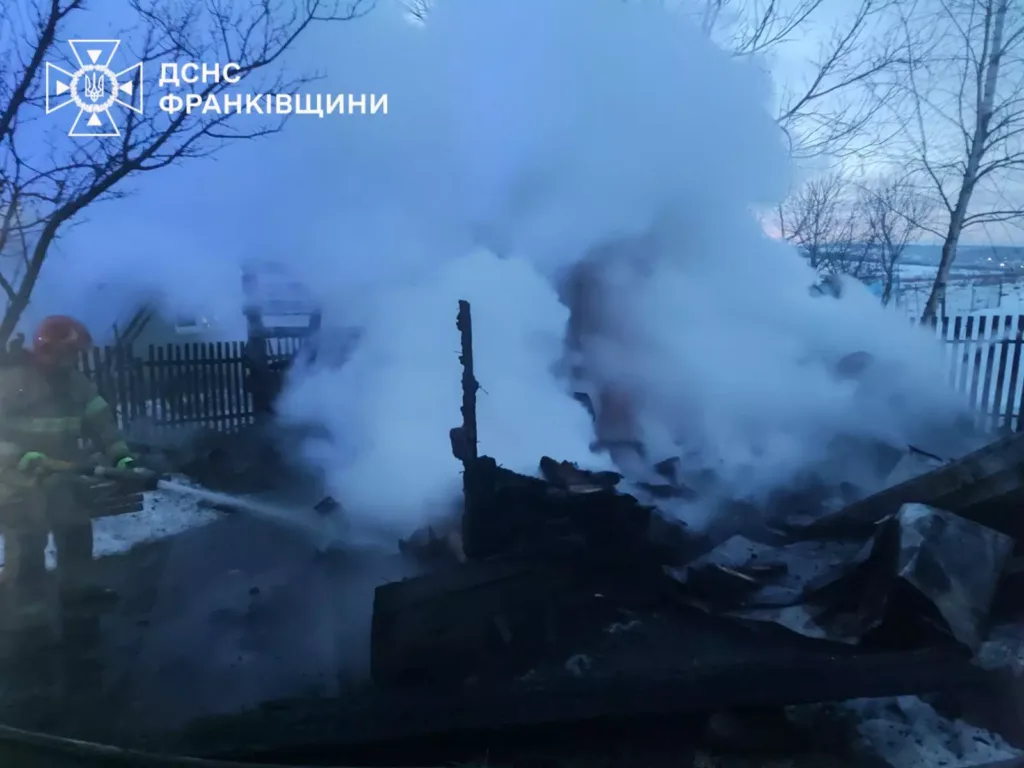 Пожежник гасить димлячу будівлю взимку