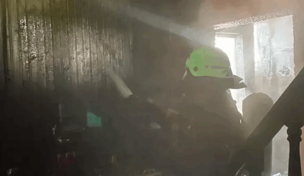 Пожежник гасить вогонь усередині задимленої будівлі