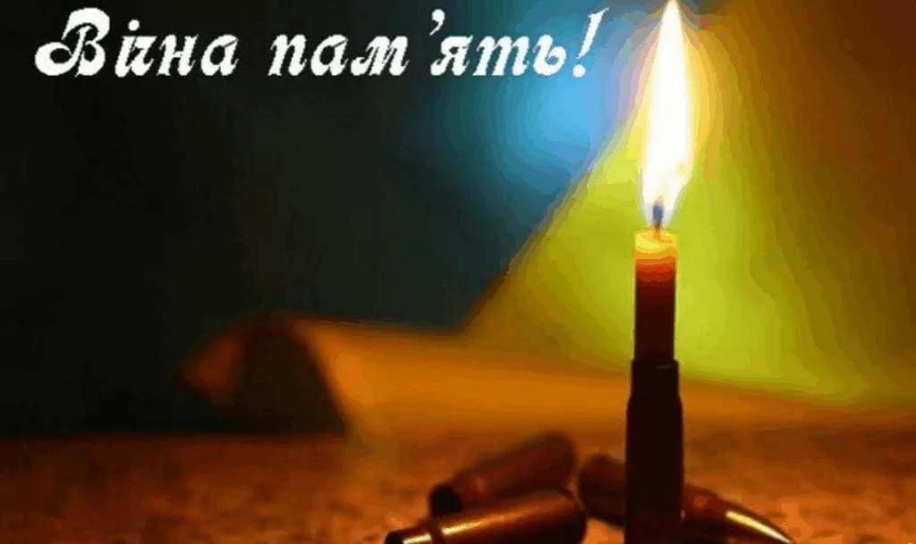 Свічка пам’яті серед гільз на тлі світла