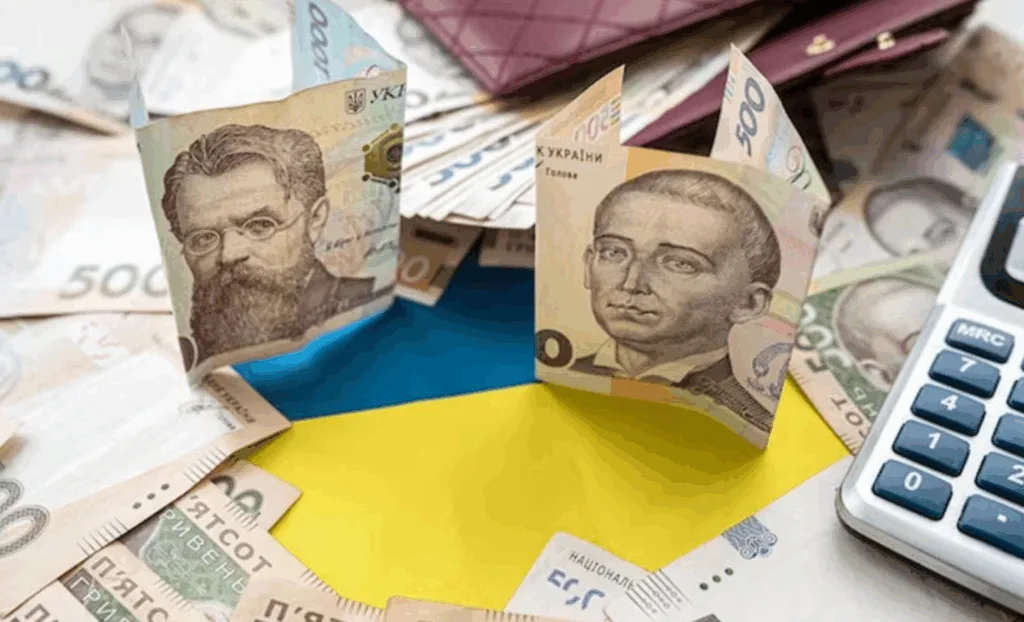 Українські гривні на фоні прапора України