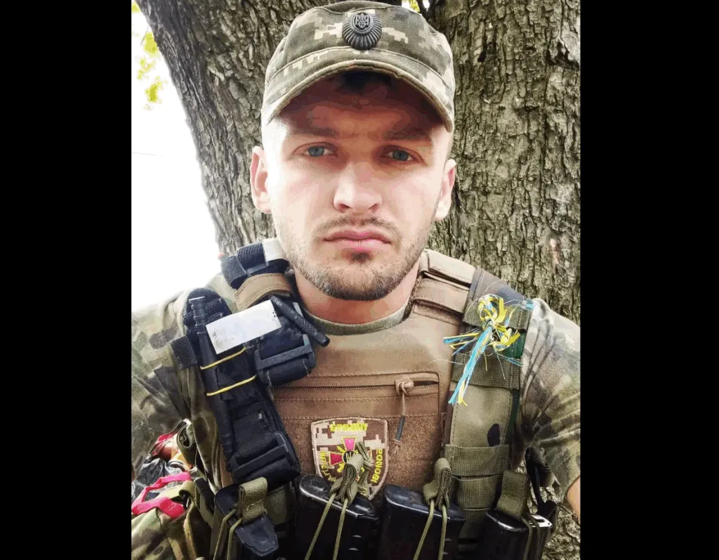 Український військовий у камуфляжі перед деревом