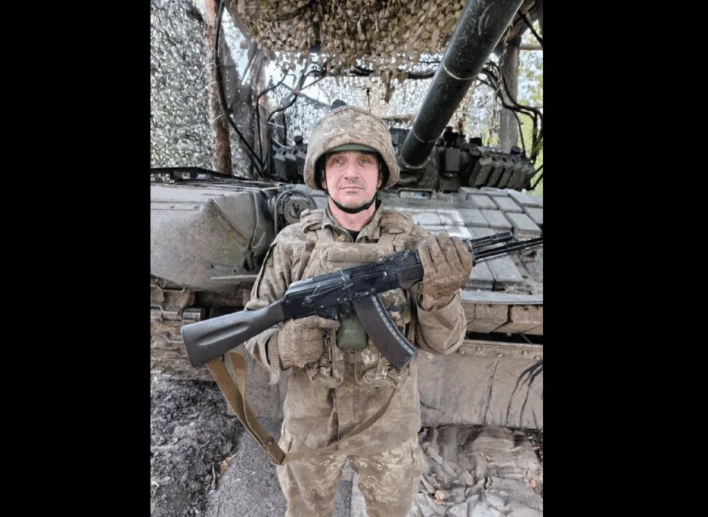 Український солдат з автоматом перед бронетехнікою