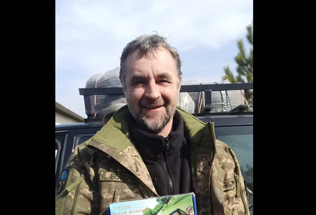 Військовий чоловік усміхається перед автомобілем