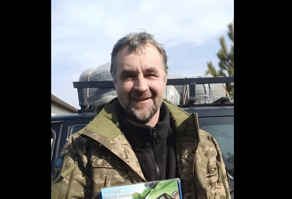 Український військовий з посилкою на фоні авто