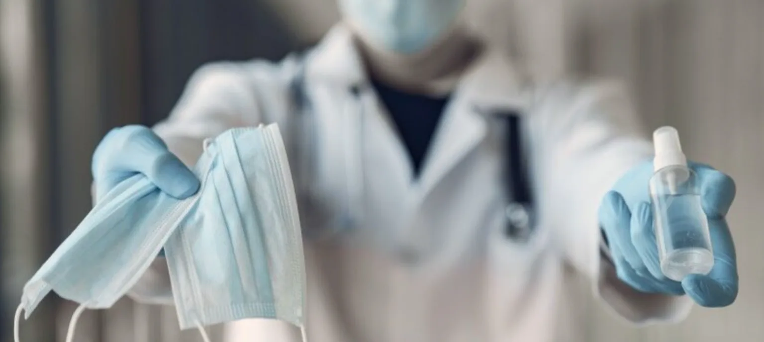 Медик тримає маски та антисептик у рукавичках