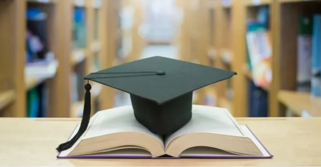 Випускна шапка на відкритій книзі у бібліотеці