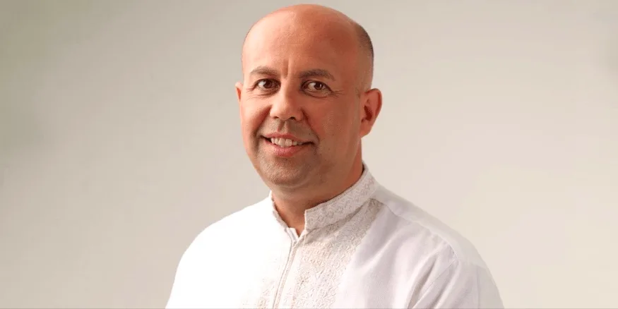 Чоловік у білій сорочці посміхається