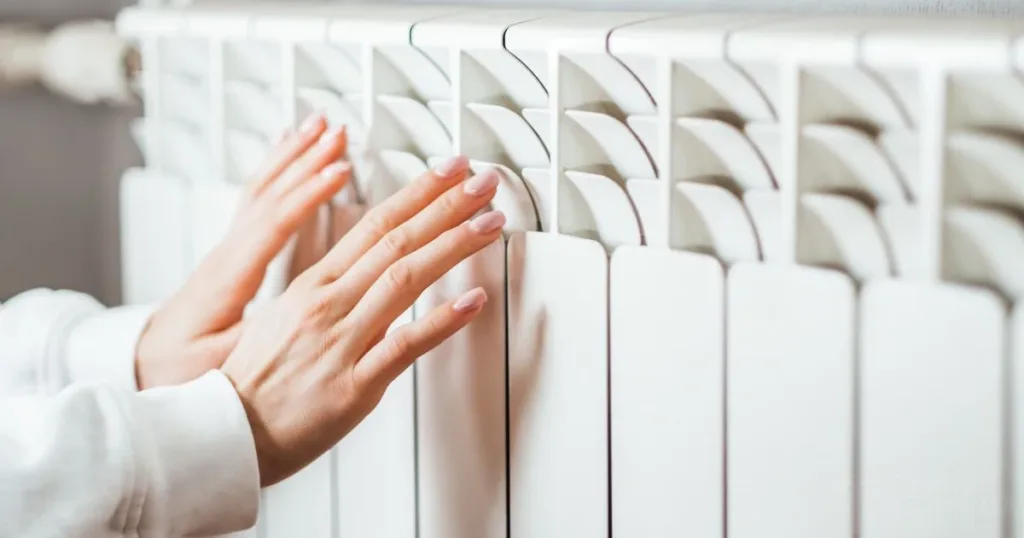 Руки біля теплого радіатора опалення