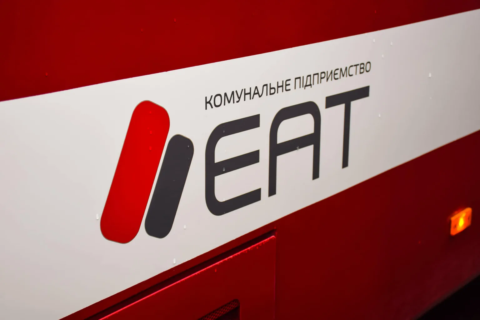 Логотип комунального підприємства EAT на червоному тлі