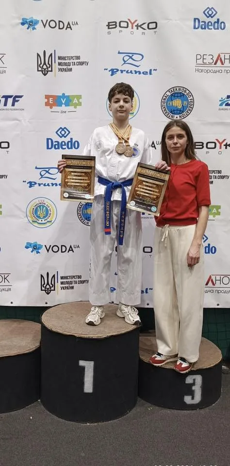 Переможець тхеквондо з медалями та тренером на подіумі