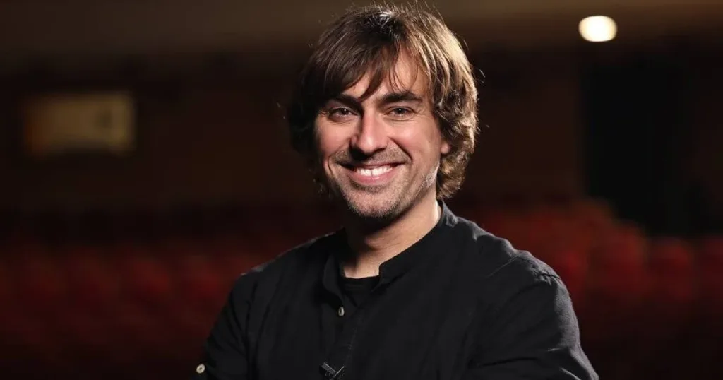 Усміхнений чоловік у чорній сорочці в залі