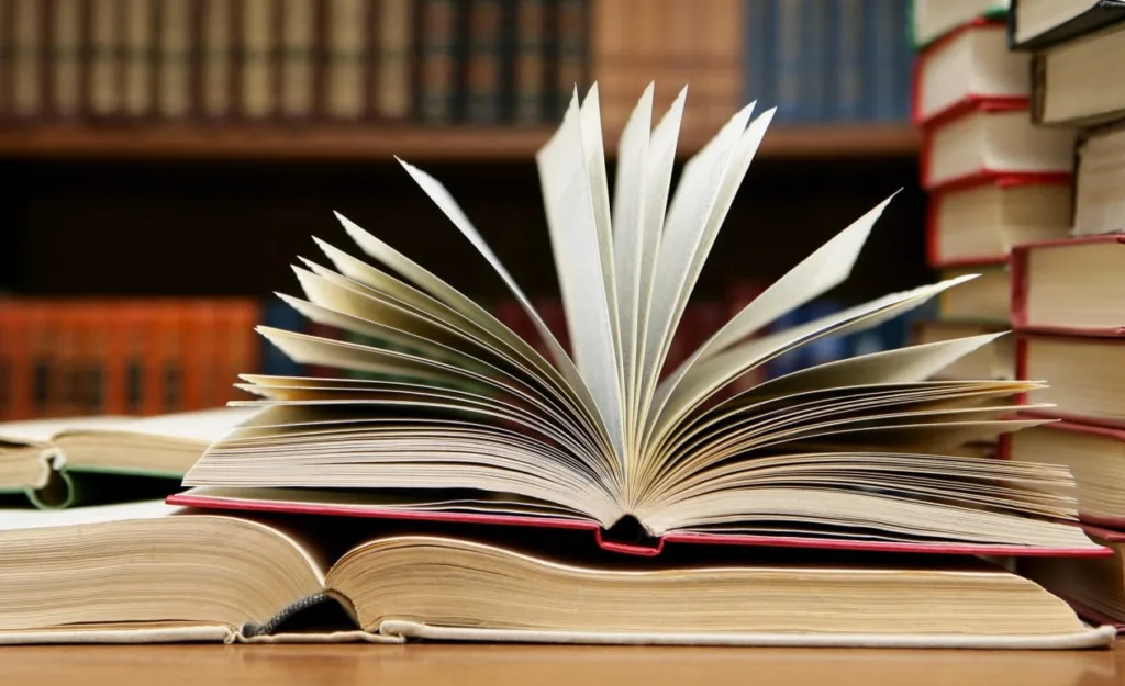 Відкрита книга на столі серед книжок