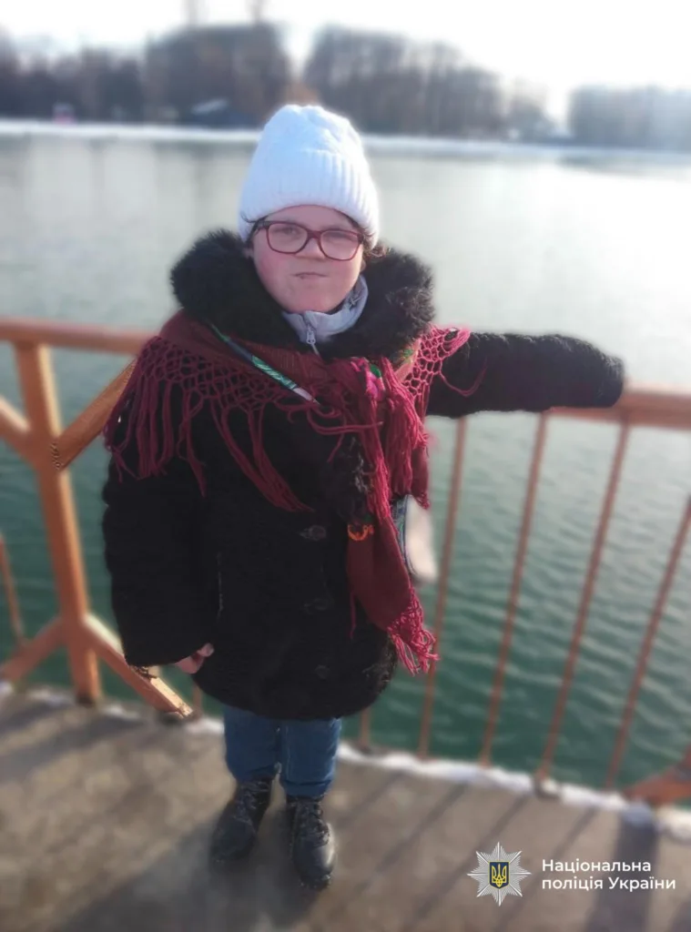 Дівчина в зимовому одязі стоїть біля води