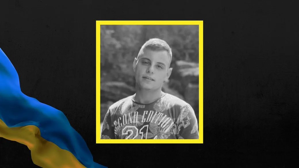 Портрет молодого чоловіка на чорному тлі з прапором України