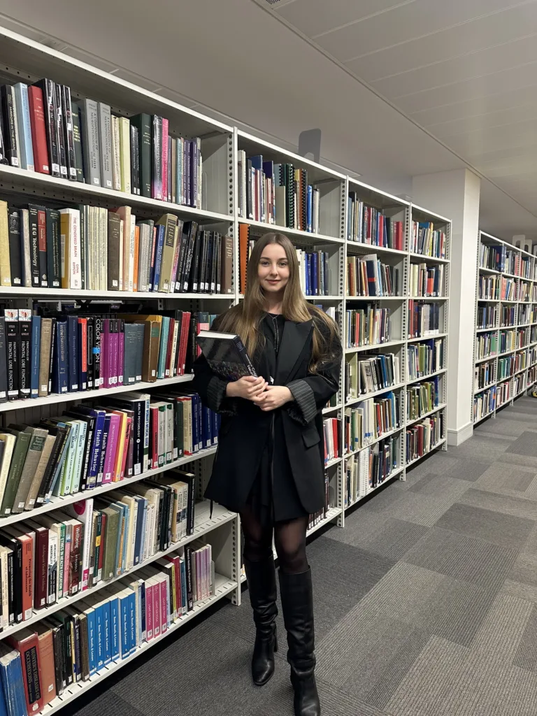 Жінка тримає книги в бібліотеці