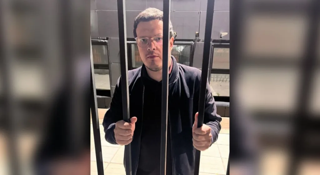 Чоловік стоїть за ґратами на вулиці