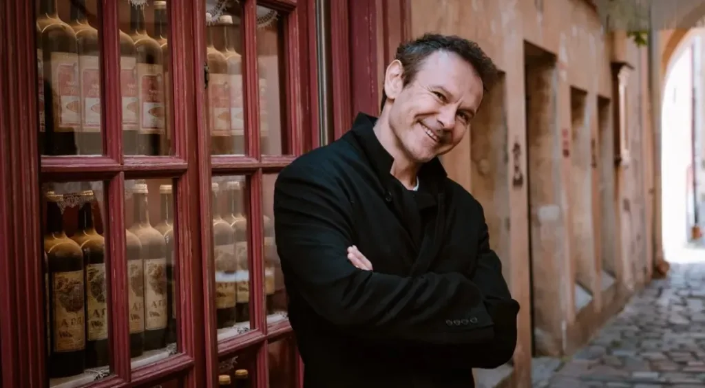 Чоловік усміхається на вулиці старого міста