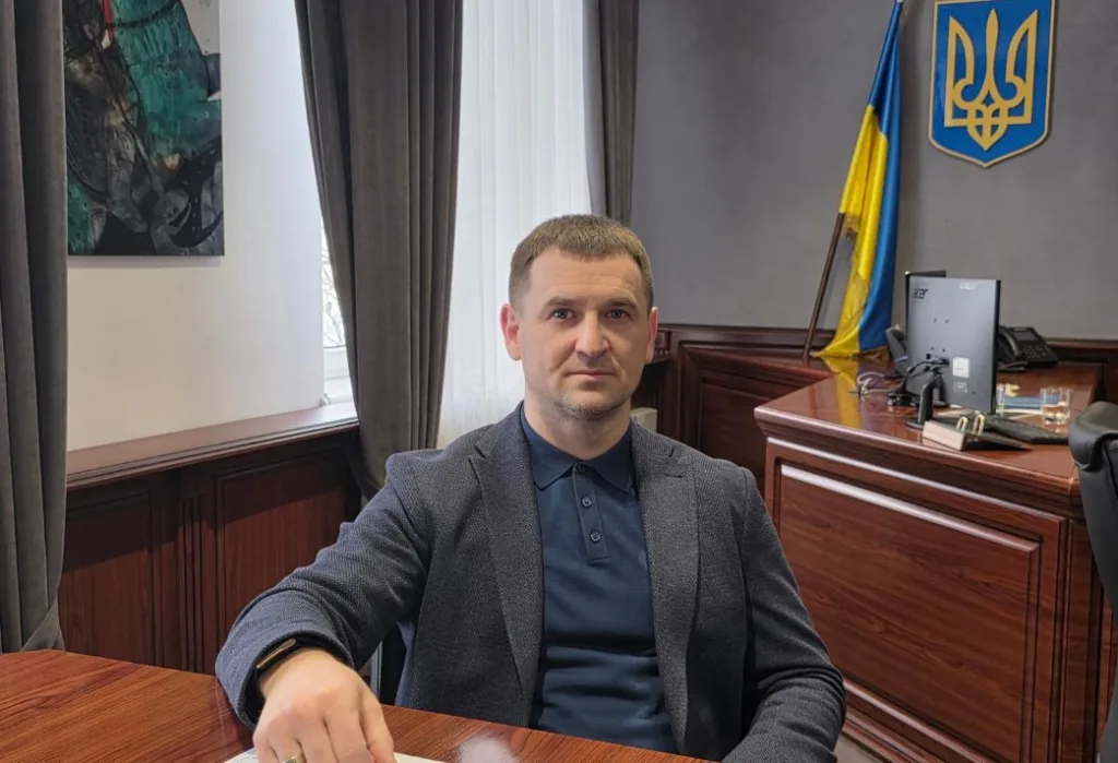 Чоловік у кабінеті біля українського прапора