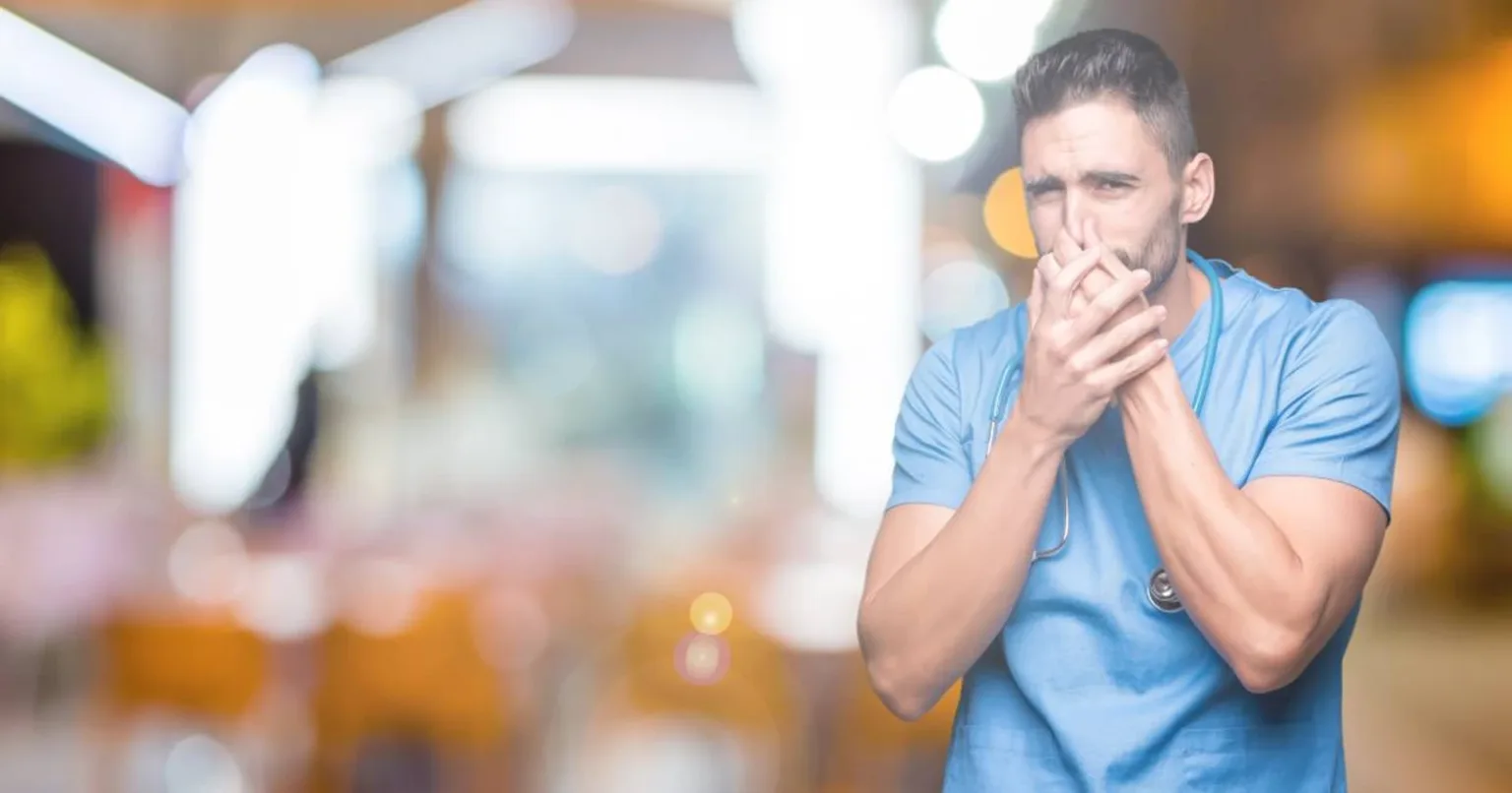 Медик затуляє ніс і рот руками