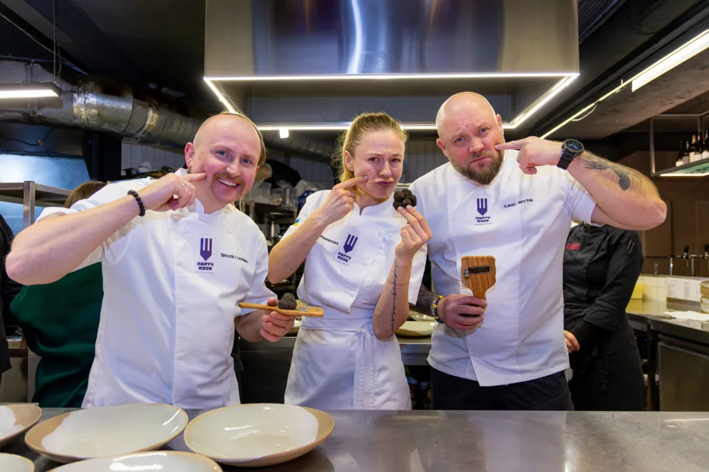 Три кухарі готують страви на професійній кухні