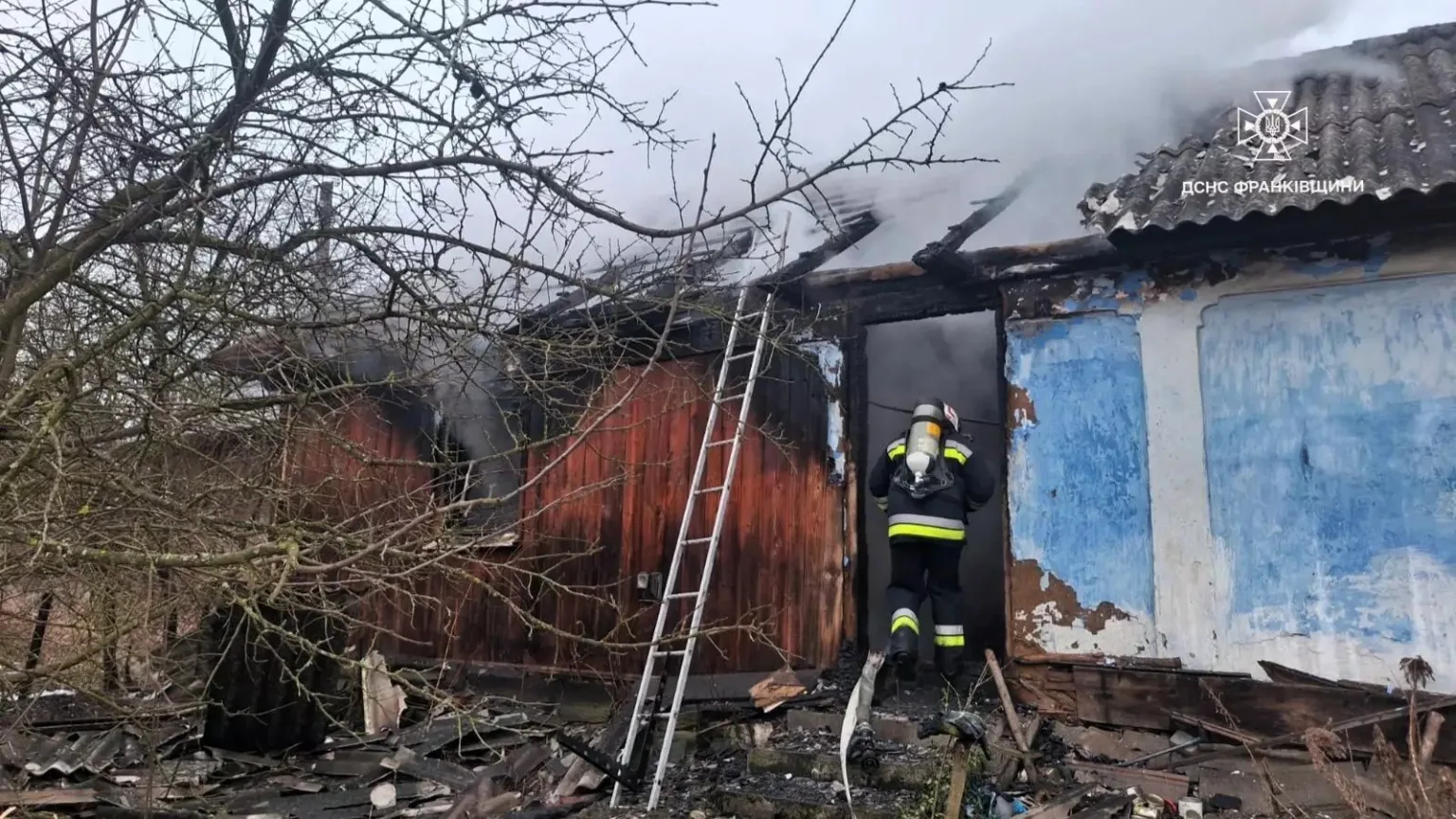 Пожежник гасить палаючий дерев'яний будинок