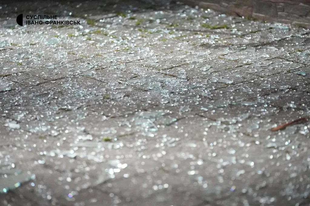Розбиті скляні уламки на бруківці вночі